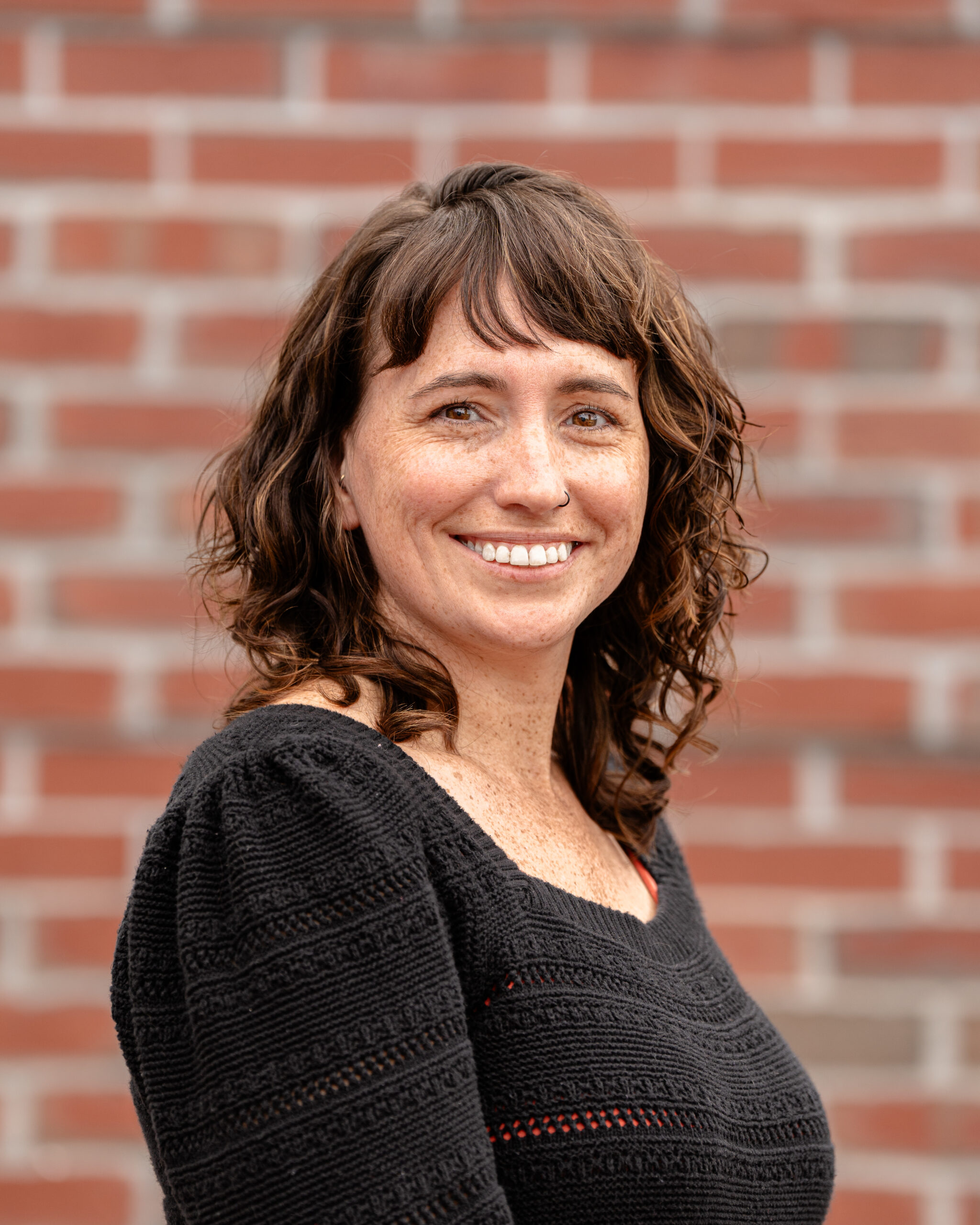 Meg, a white woman with short brown hair. She wears a black shirt.