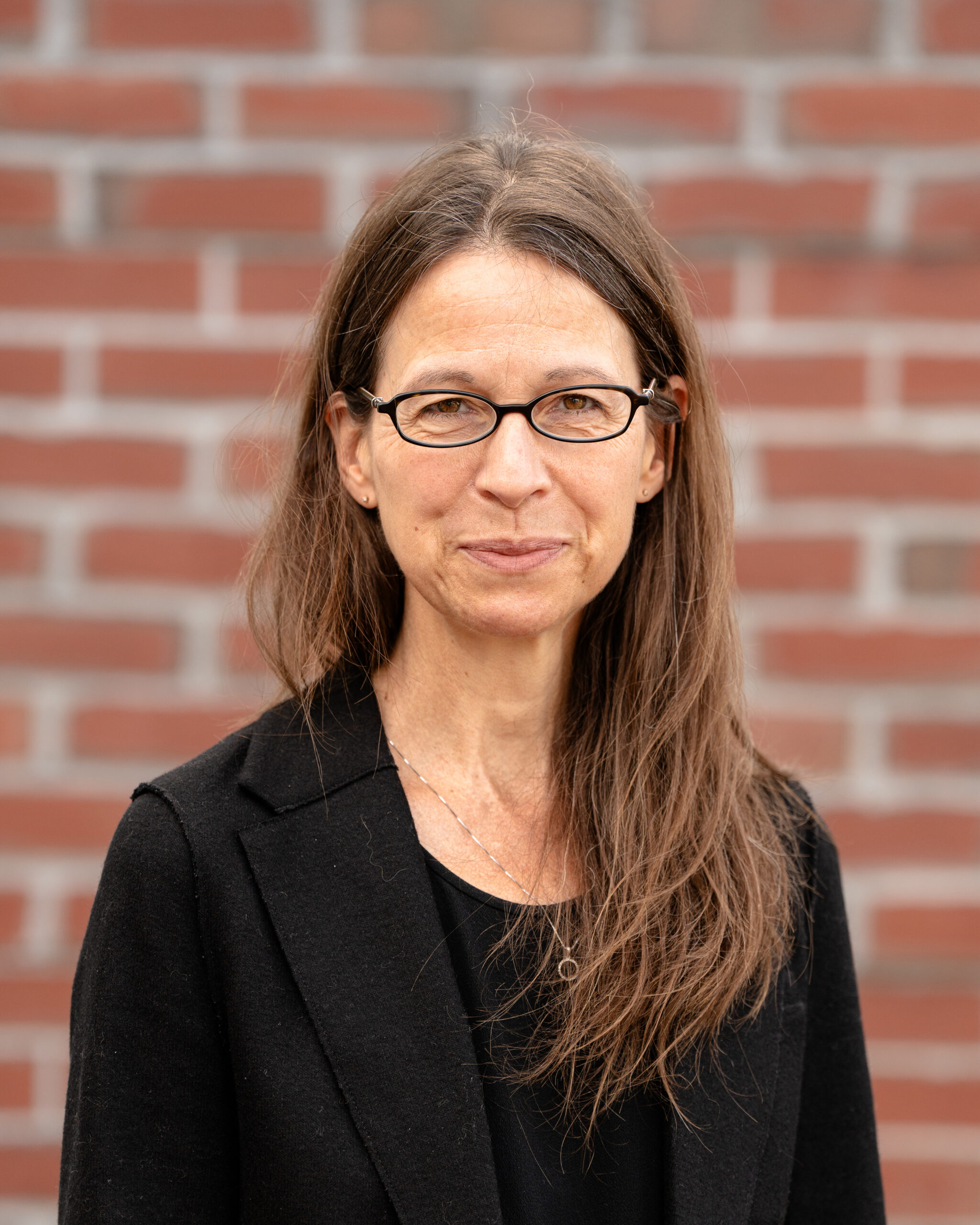 Jeanette, a white woman with long brown hair wearing a black jacket.