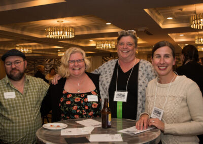 Group of four people stand and smile.
